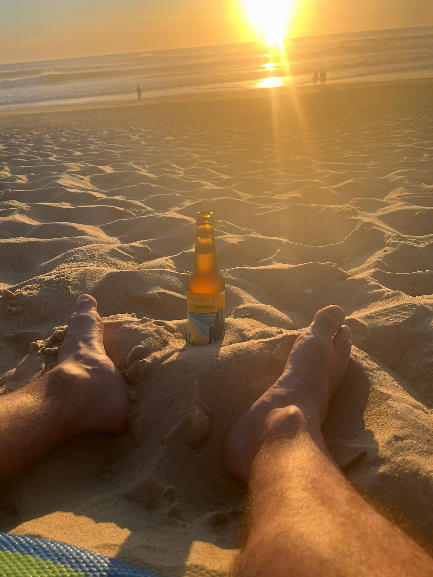 Pieds dans le sable, bière et coucher de soleil